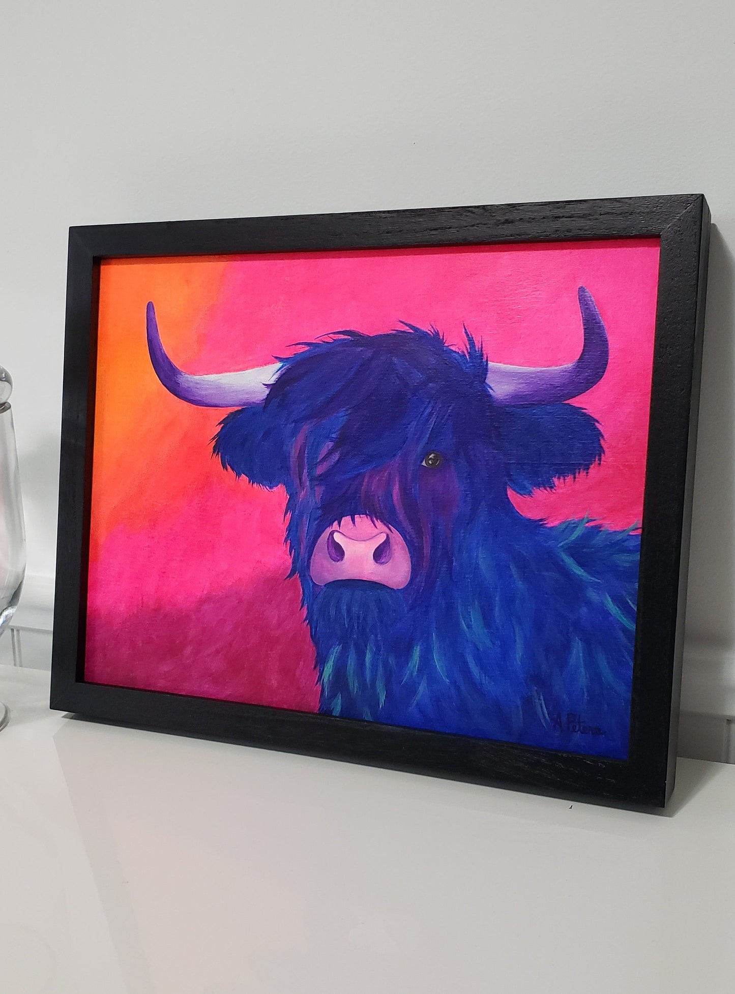 "Pretty Violet" Highland cow acrylic painting on canvasboard. Fluorescent orange and pink background with a purple highland cow. framed in a black wooden frame.